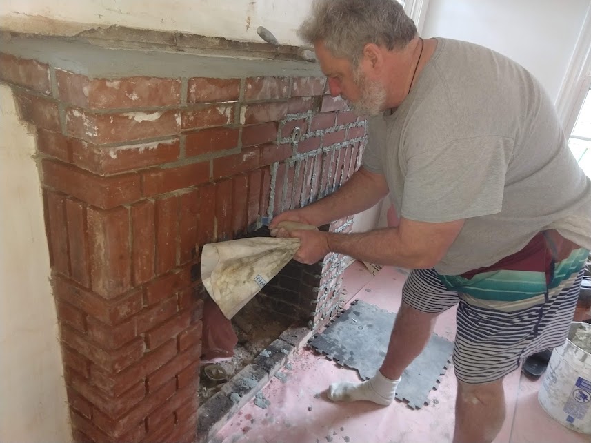 Man repointing brick fireplace for renovation.