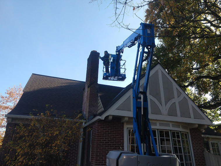 Worker in lift inspecting house chimney.