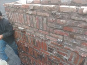 Person behind a weathered brick wall.