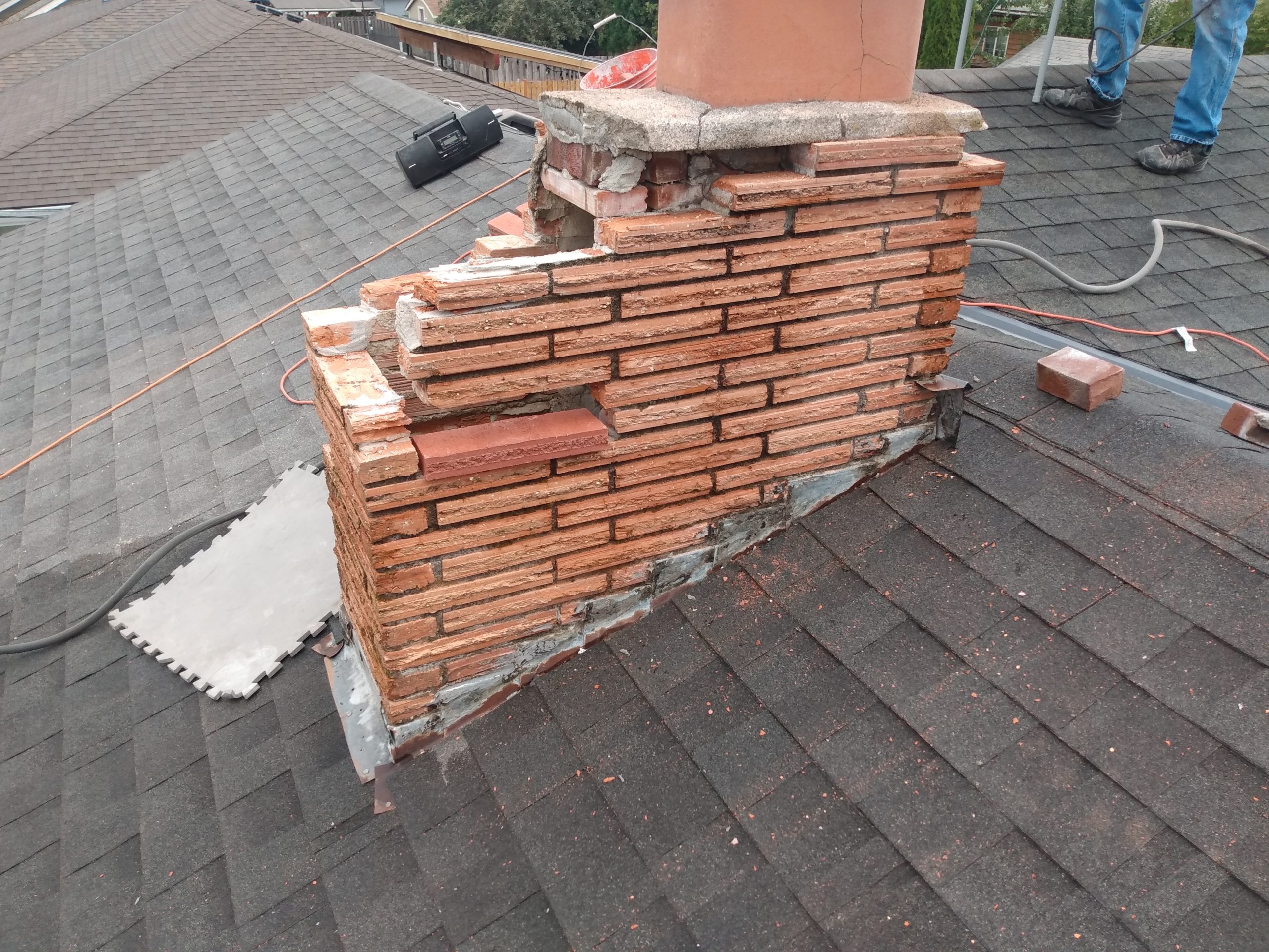 Damaged chimney bricks on residential rooftop.