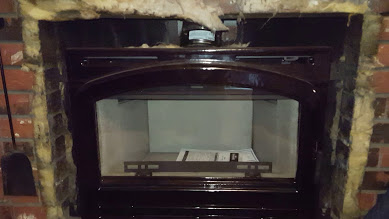Brick fireplace with installed wood stove insert.