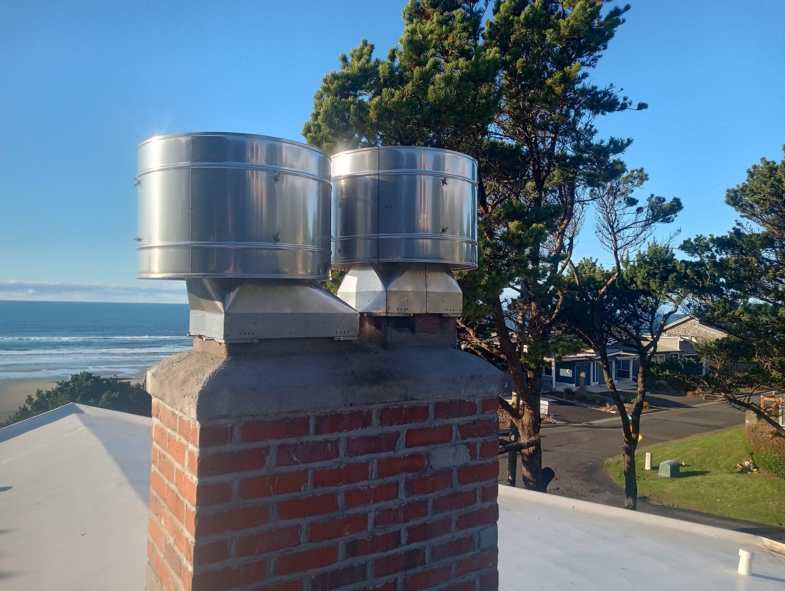 Newport Oregon Monsoon chimney rain caps Stainless steel Monsoon rain caps installed on a chimney in Newport, Oregon. No rain can blow into the caps. Caps prevent wind downdrafts.